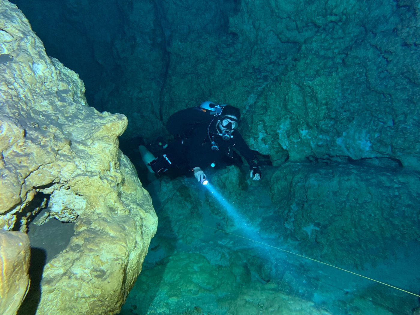 A diver lighting a rock wall with a hand torch